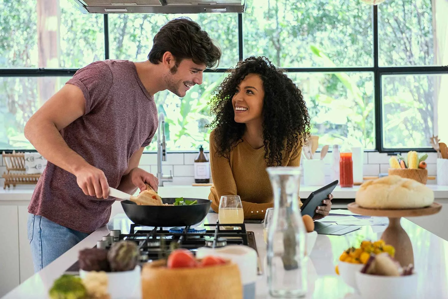 Lächelndes Paar beim Kochen mit Tablet in der Küche