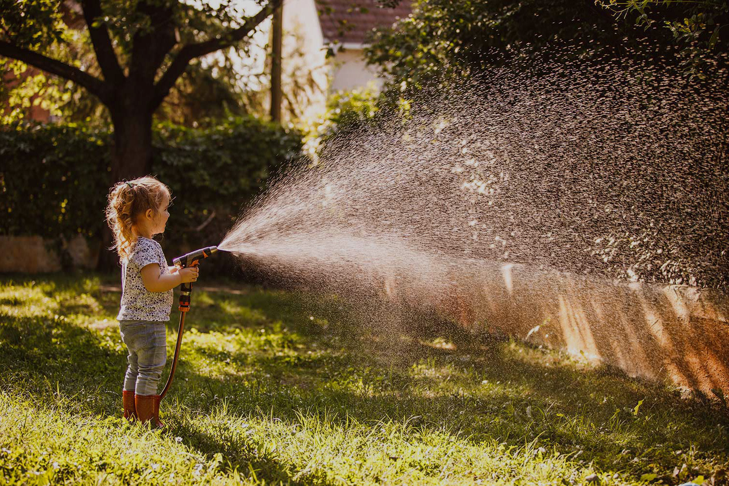 Kleine Gärtnerin wässert Garten.