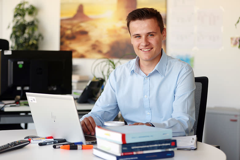 EWR-Azubi am Schreibtisch mit Laptop und Büchern