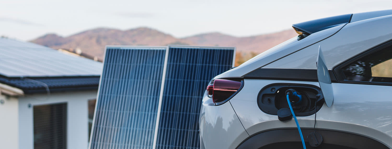 Elektroauto wird vor einem Haus mit Photovoltaik geladen
