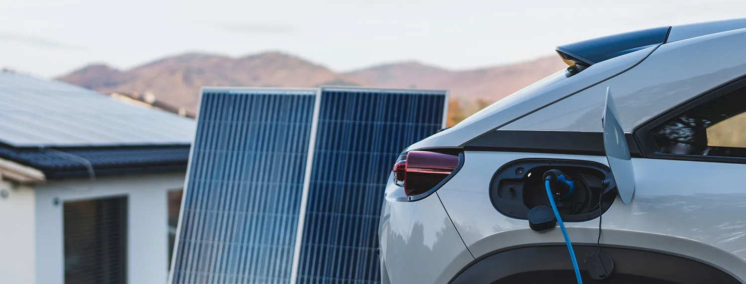 Elektroauto wird vor einem Haus mit Photovoltaik geladen