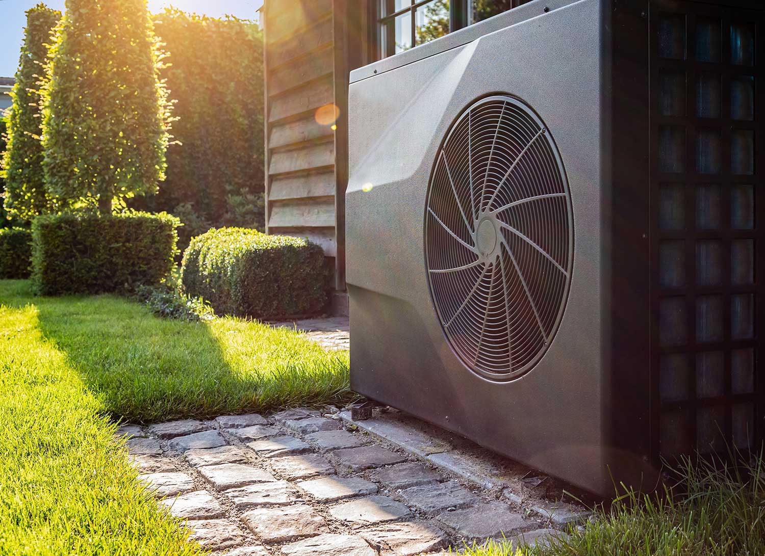 Wärmepumpe steht an Hauswand im Garten