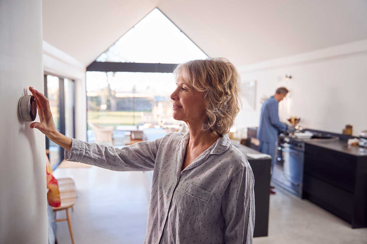 Reife Frau Einstellung Wand montiert digitale Zentralheizung Thermostat Steuerung zu Hause