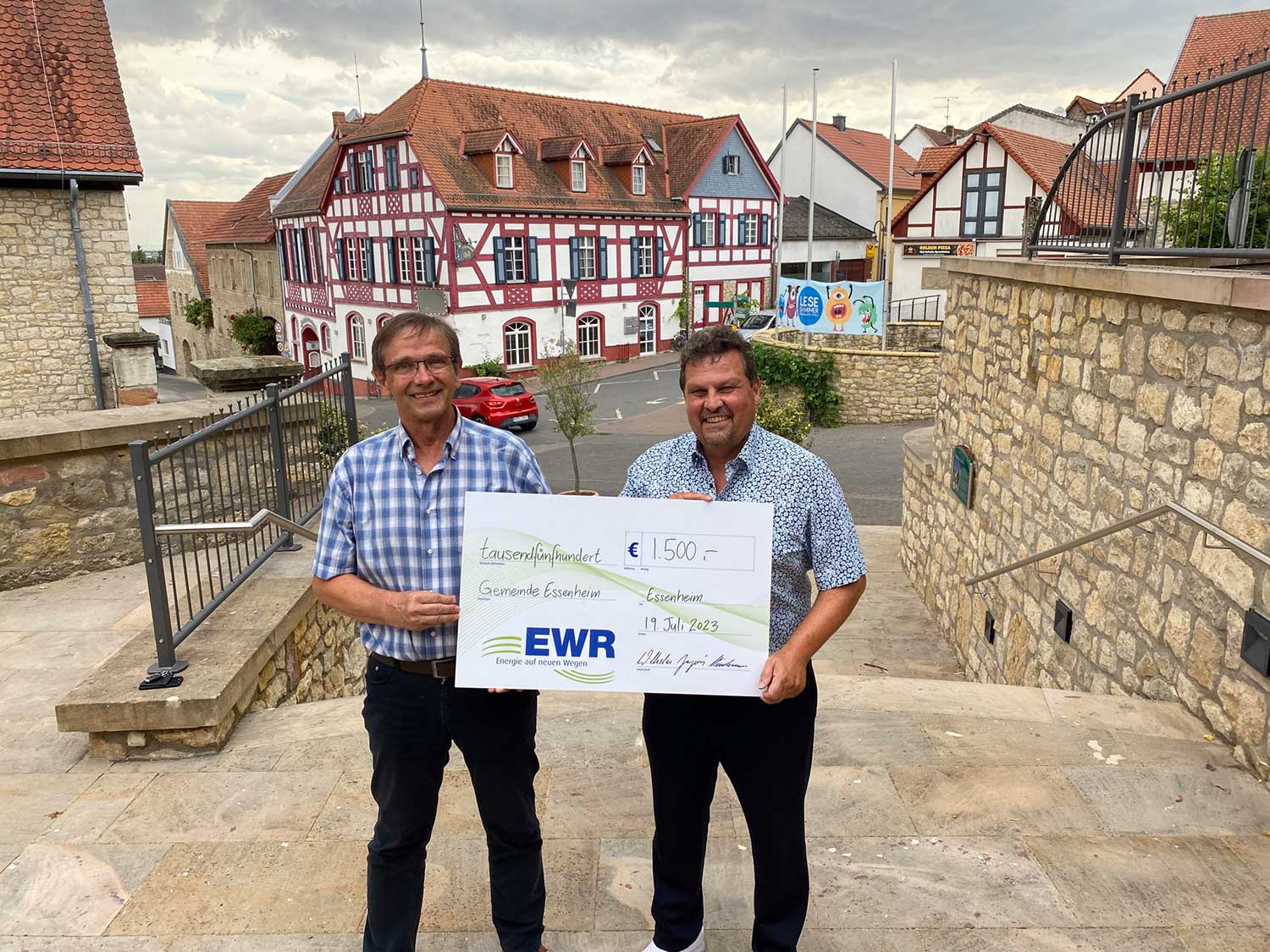 Mann übergibt einen symbolischen Scheck für die Spende der EWR Mitarbeiter Mann übergibt einen symbolischen Scheck für die Spende der EWR Mitarbeiter