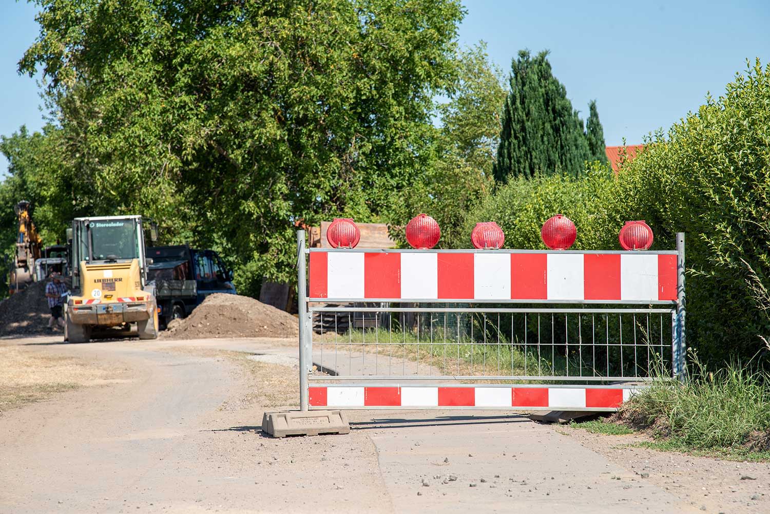 EWR Netz Baustelle mit Absperrung im Vordergrund und Bagger im Hintergrund. EWR Netz Baustelle mit Absperrung im Vordergrund und Bagger im Hintergrund.