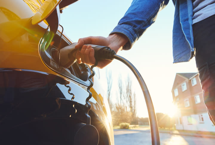 Mann lädt Elektroauto vor Haus
