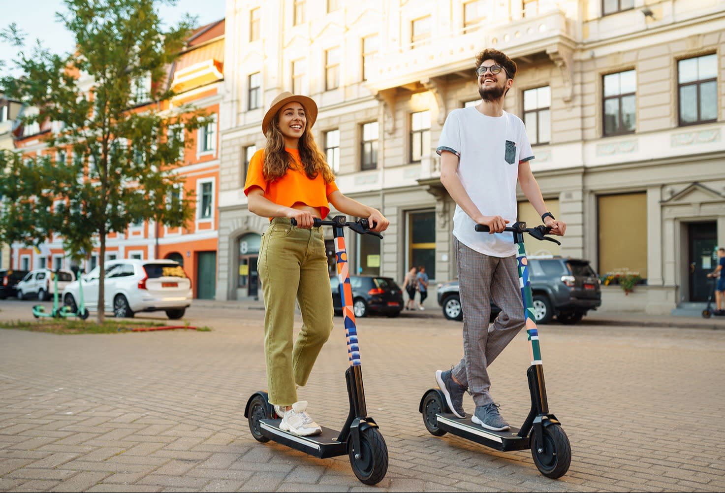 Junges Paar, das Spaß daran hat, mit dem Elektroroller durch die Stadt zu fahren