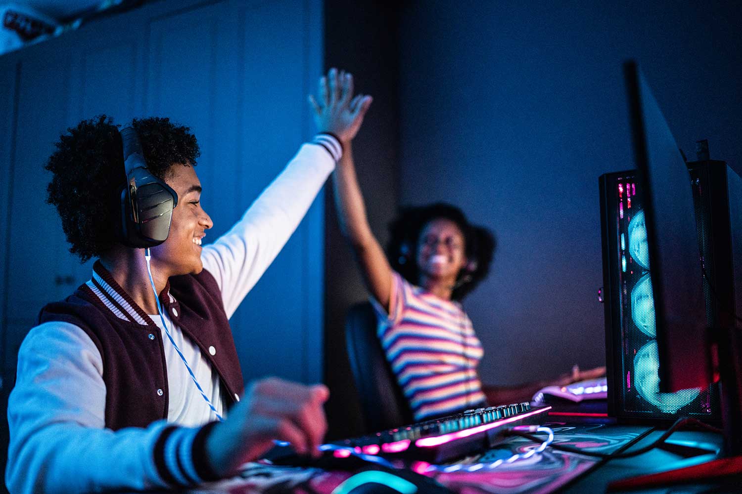 Freunde, die ein High Five machen, während sie zu Hause am Computer spielen