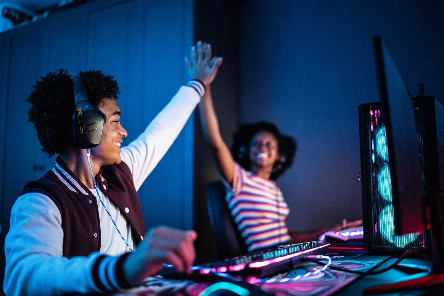 Freunde, die ein High Five machen, während sie zu Hause am Computer spielen