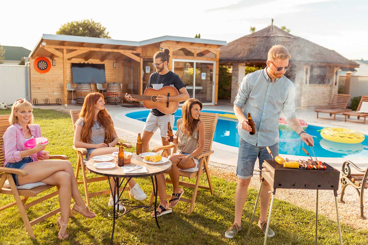 Freunde grillen im Garten mit Pool