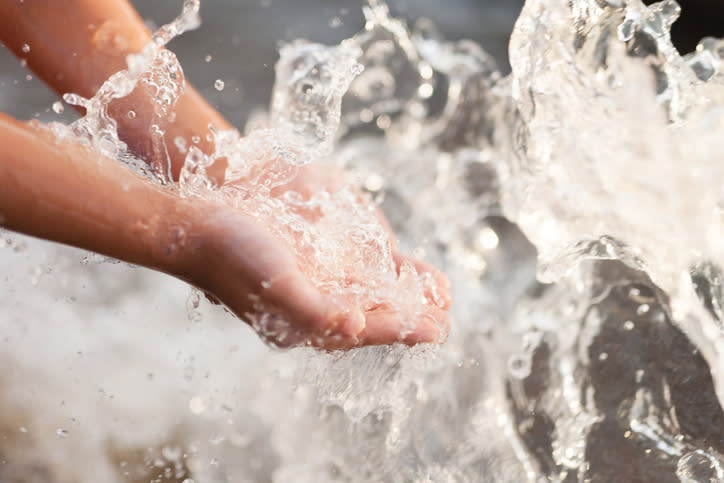 Hände greifen in spitzendes Wasser