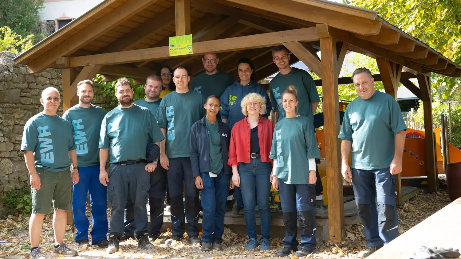 Titelbild Personengruppe steht unter einer Holzüberdachung