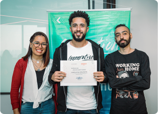 3 people stand together, smiling at the camera. The person in the centre holds a certificate at the NGO Generation graduation. A green banner in the background displays 'Generation'