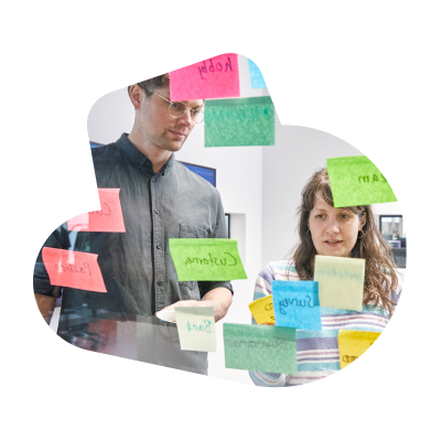 A male and a female SumUp employee working with colourful sticky notes on a glass.