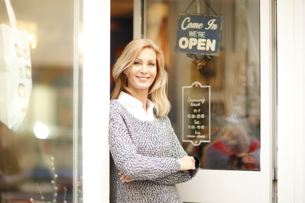 Portrait of designer woman standing in front of small vintage store. Small business