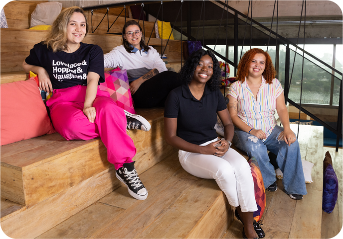 4 young female engineers of diverse backgrounds, sitting on the stairs at the SumUp office in Brazil.