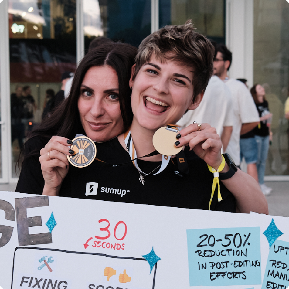 Two SumUppers smiling and holding medals while celebrating their team’s project achievement at SumUp Hack Week