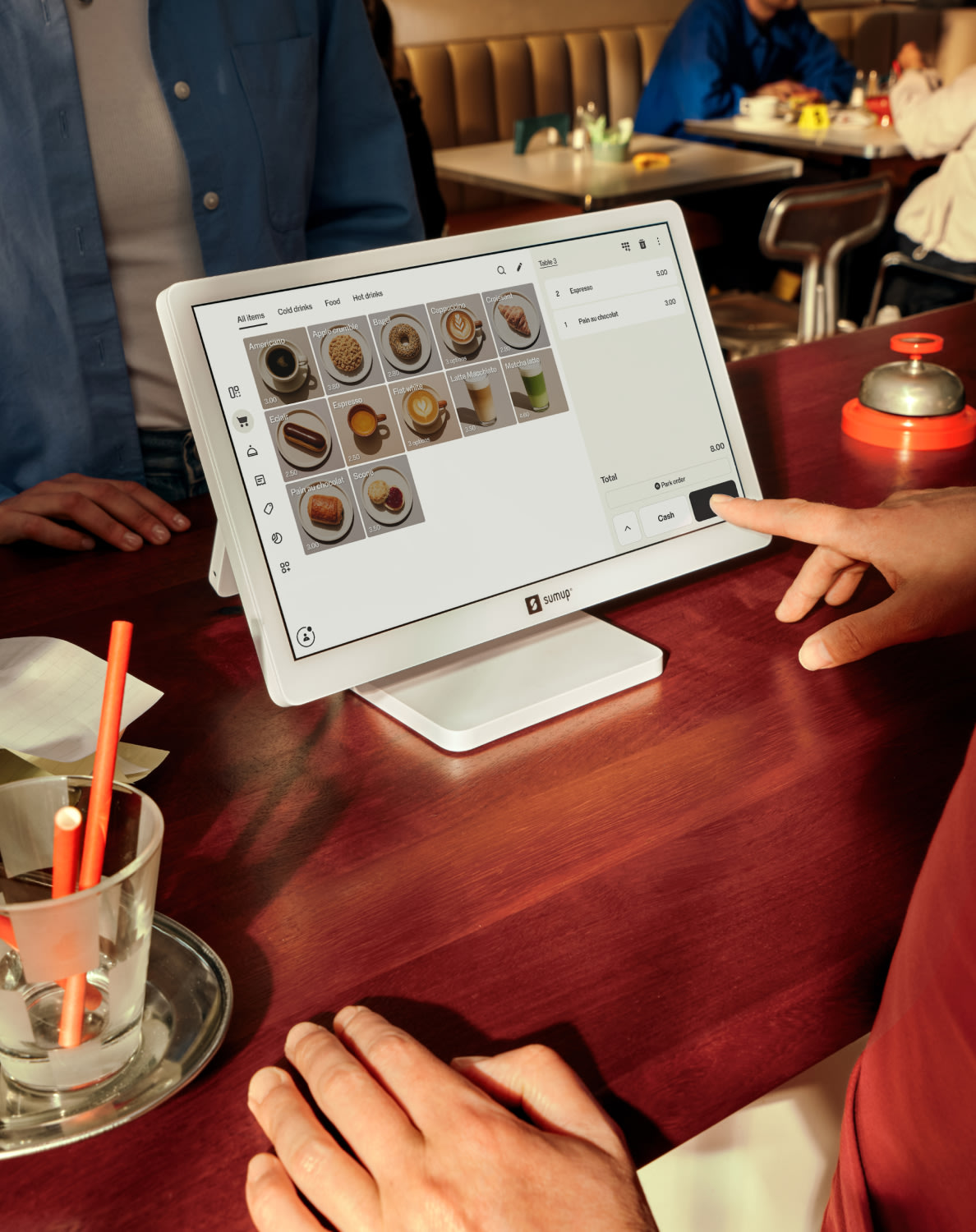 A customer interacts with a digital menu screen displaying food and drink options at a restaurant table