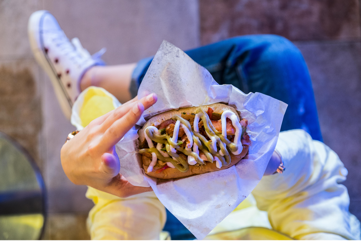 Kundin mit Hotdog am eigenen Imbiss