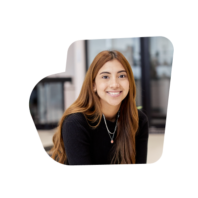 A female intern smiling at the camera, wearing a black turtle neck shirt and long brown hair.