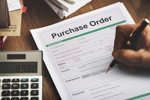Purchase order on desk with person holding pen