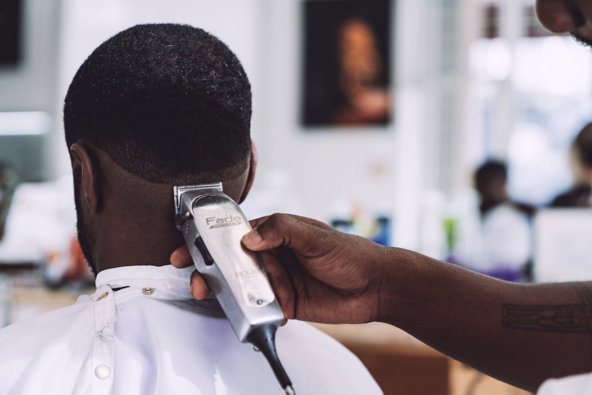 Men at barber is getting hair cut.