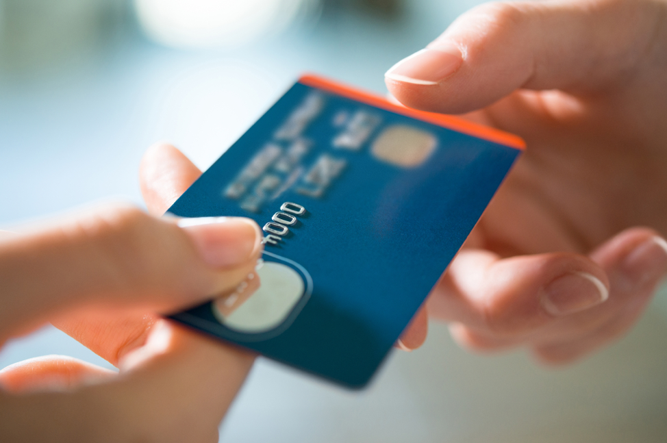 A credit card being passed between two people.