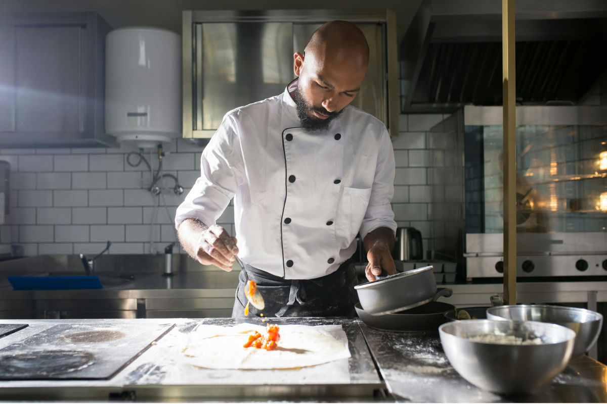 Mann kocht mit Fett in Gastronomie Küche