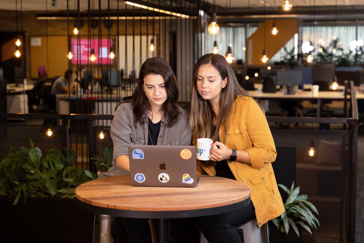 Two brunette female SumUppers working in front of a laptop in an office environment 