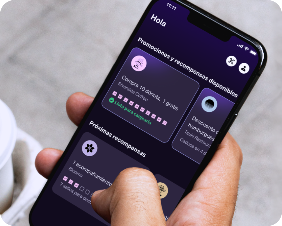 Una mano sujeta un teléfono móvil con la aplicación SumUp Pay; en ella se muestran varias tarjetas del programa de fidelidad.