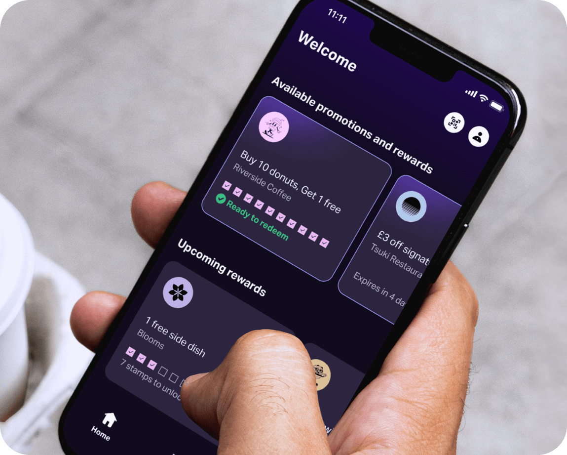 A hand holding a mobile phone with the SumUp Pay app showing several loyalty programme cards.