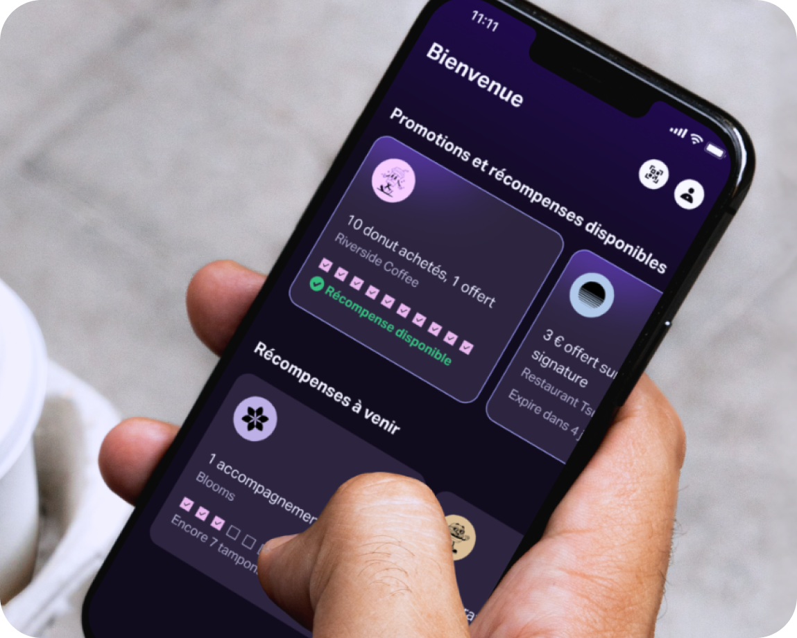 Une main tenant un téléphone mobile avec l'application SumUp Pay montrant plusieurs cartes de fidélité.