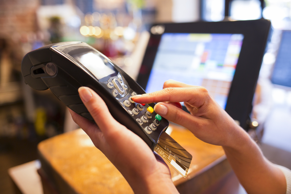 A woman uses a credit card machine to complete a transaction.