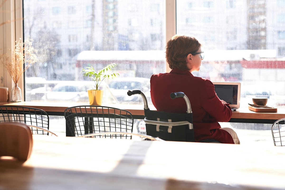 Frau sitzt in Restaurant und arbeitet an Laptop