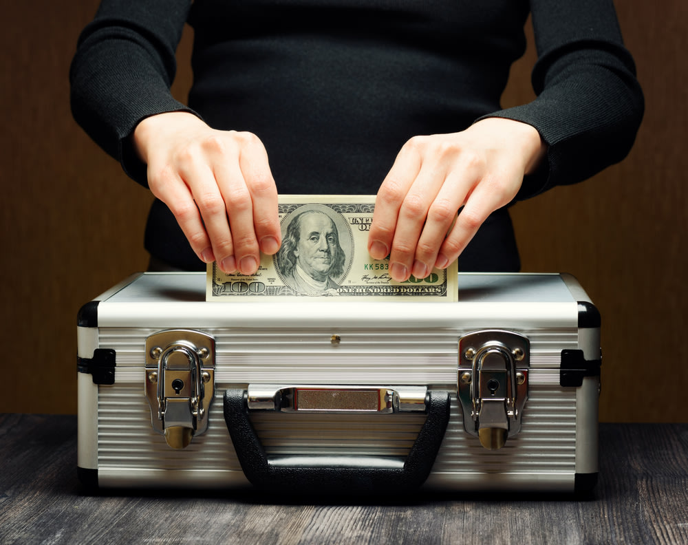 Person holding cash on top of a safe box