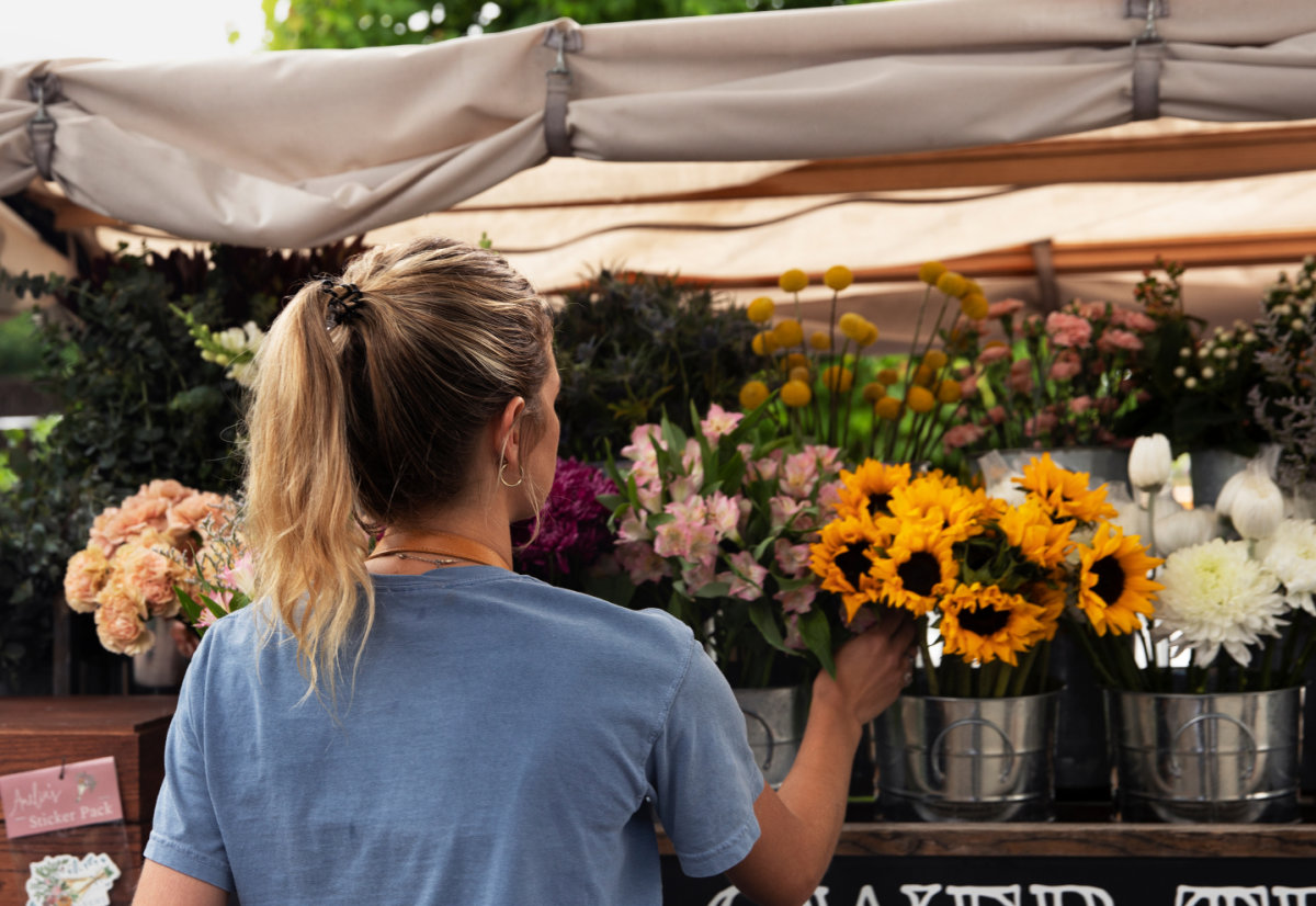 Como começar um negócio com pouco dinheiro - Dona de floricultura cuidando carinhosamente de girassóis, simbolizando o início bem-sucedido de um negócio de flores com recursos limitados.