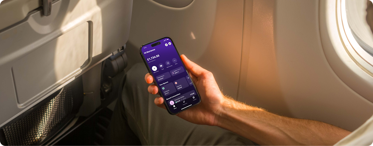 Passenger in an airplane window seat checks the SumUp Pay app on their phone, viewing balance and recent transactions.
