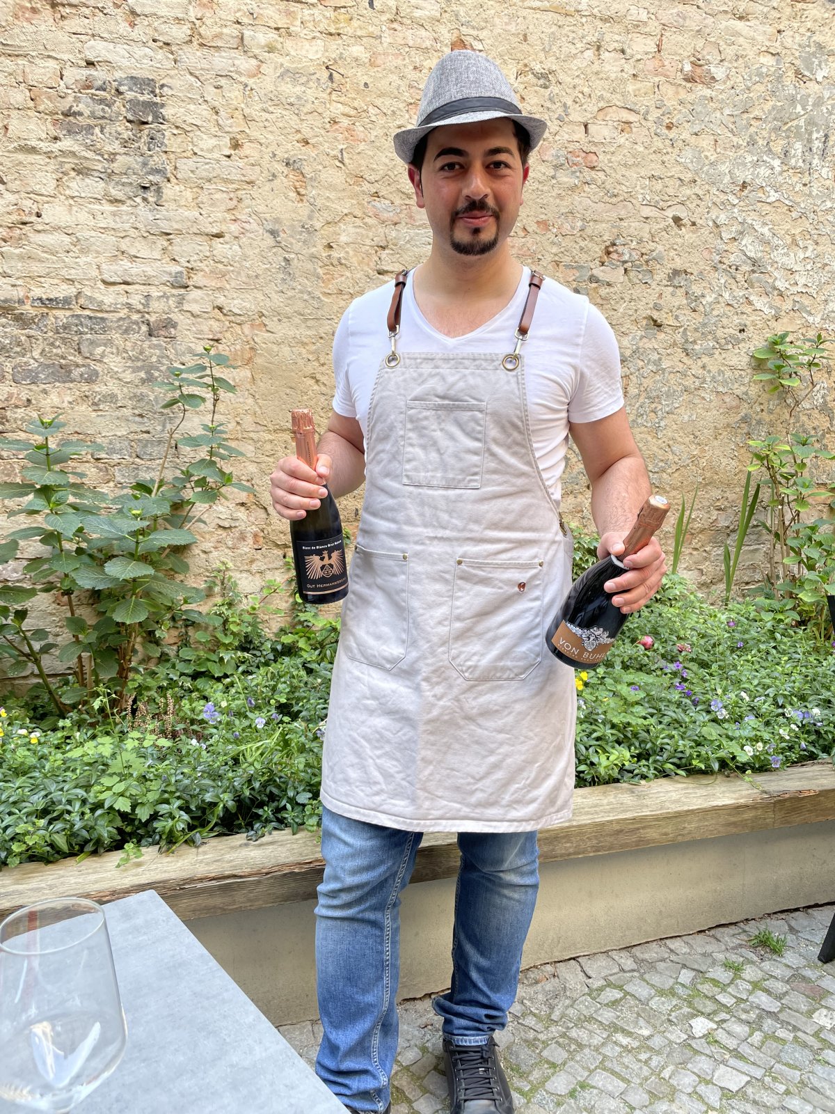 Geschäftsinhaber Serhat Aktas posiert mit 2 Flaschen Wein in der Hand