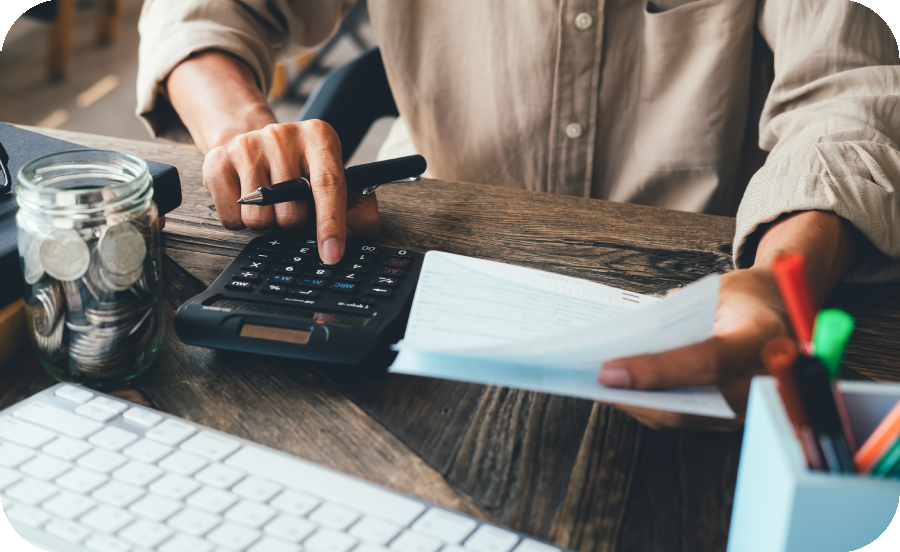 Image of a person holding papers and typing into a calculator