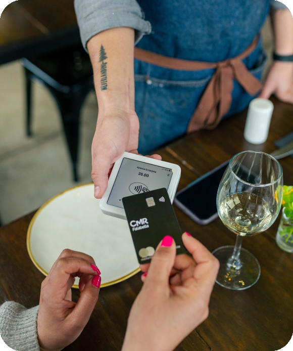 Image d’un serveur tenant un terminal de paiement SumUp Solo et d’un client qui présente sa carte pour payer sans contact.