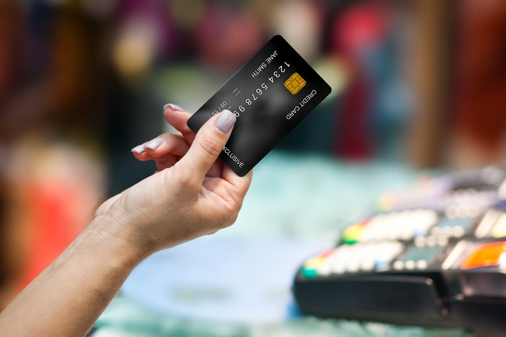Woman's hand holding a black EMV chip credit card.