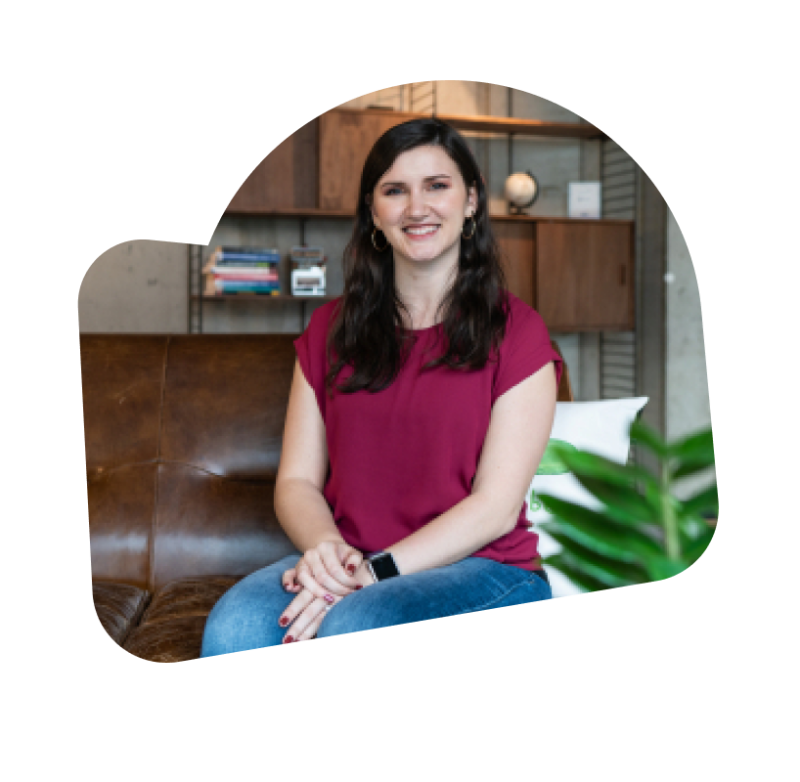 A female engineer sitting on a sofa, smiling at the camera and wearing a red shirt