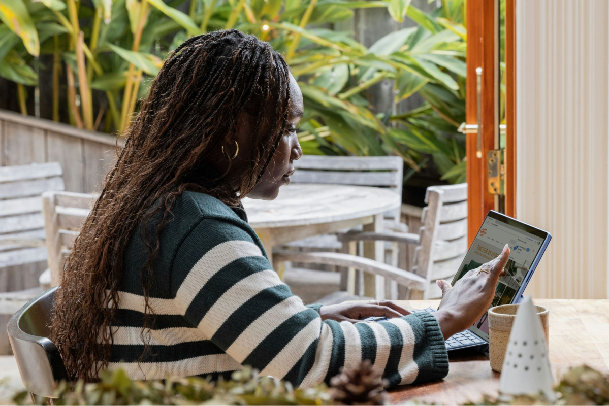 Eine Frau mit langen Haaren sitzt und arbeitet an einem Tablet 