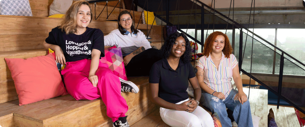 4 young female engineers of diverse backgrounds, sitting on the stairs at the SumUp office in Brazil.