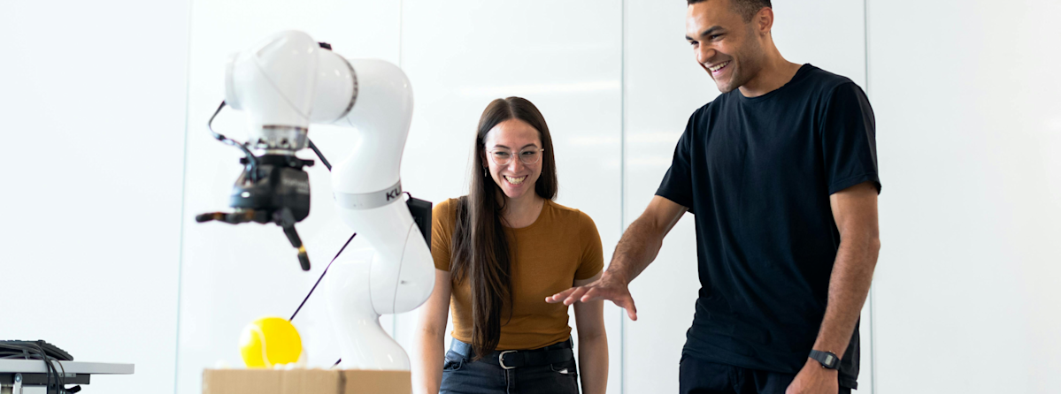 Frau und Mann mit Roboter in Fabrik
