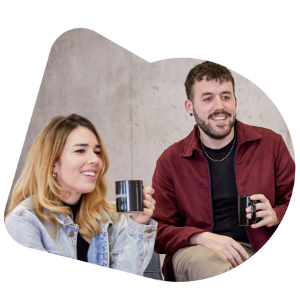 A female and a male SumUpper smiling and holding a branded SumUp black mug.