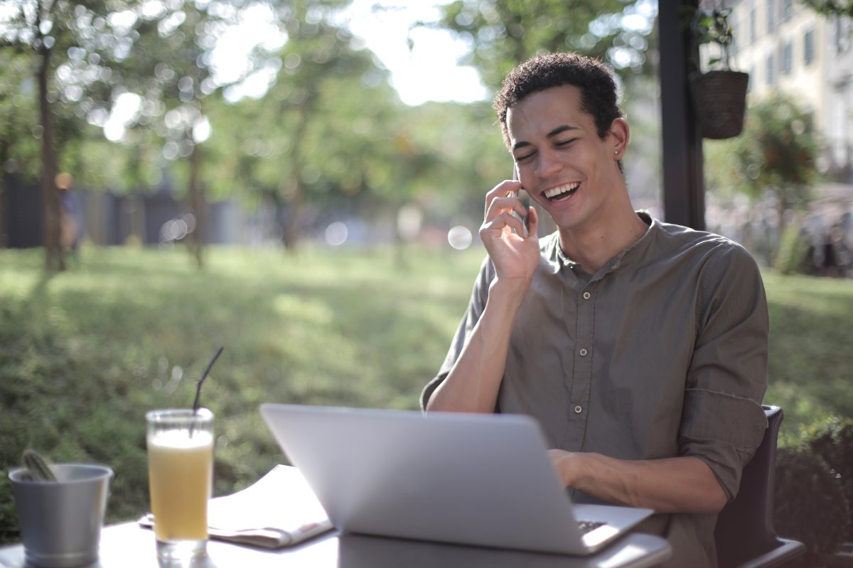 Mann arbeitet im Park und telefoniert mit dem Kundenservice seiner Kassensoftware