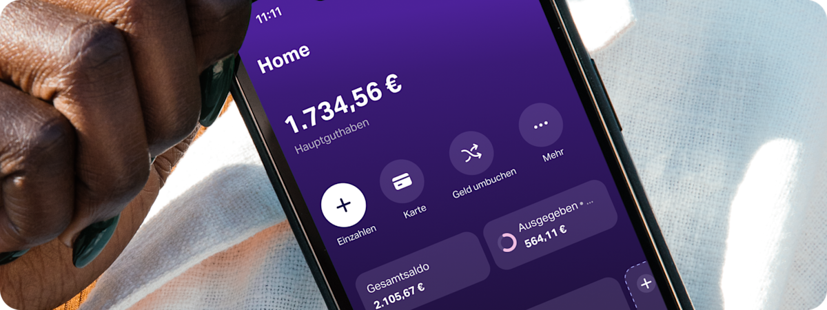 Nahaufnahme einer Hand, die ein Smartphone mit der SumUp Pay App hält, auf der ein „Reisekasse“-Budget-Space zu sehen ist.