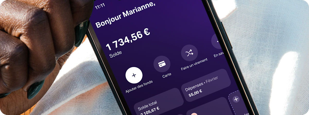 Plan rapproché d'une main tenant un smartphone qui affiche l'application SumUp Pay, montrant un espace d'économies pour un « City-trip ».