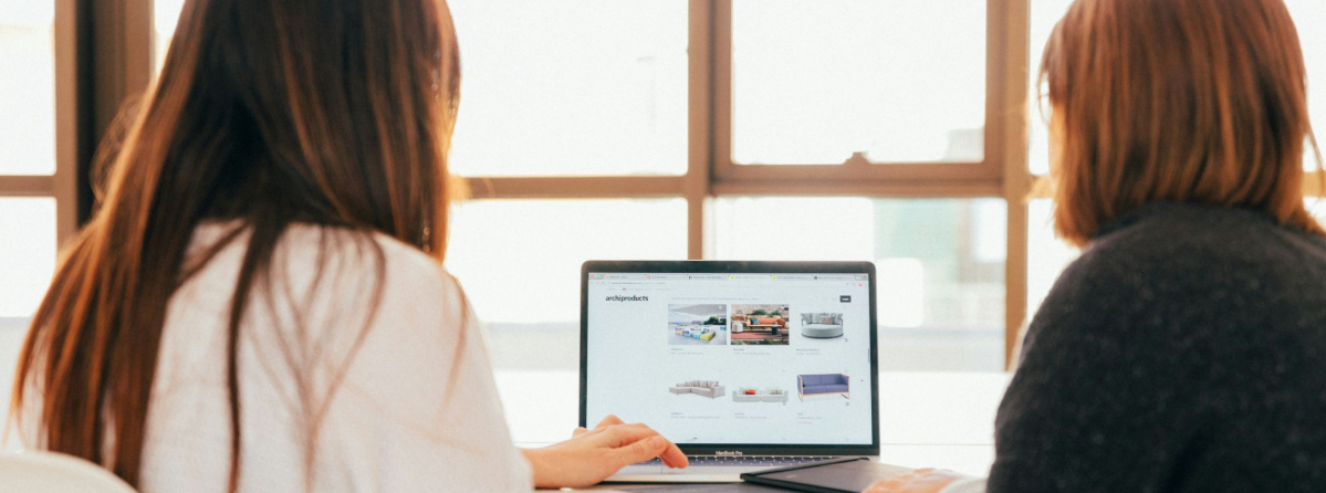 Zwei Frauen sitzen am Tisch vor einem Laptop